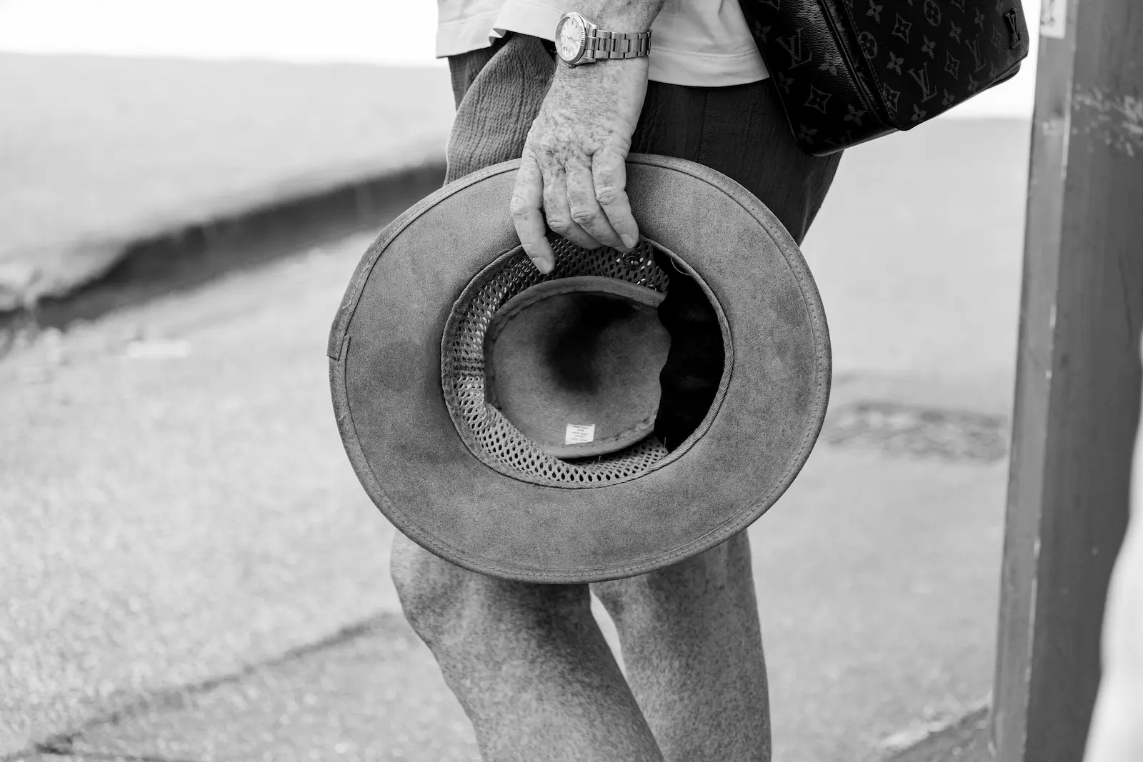 Detalle en blanco y negro de una mano mayor sujetando un sombrero de ala ancha, fotografía documental