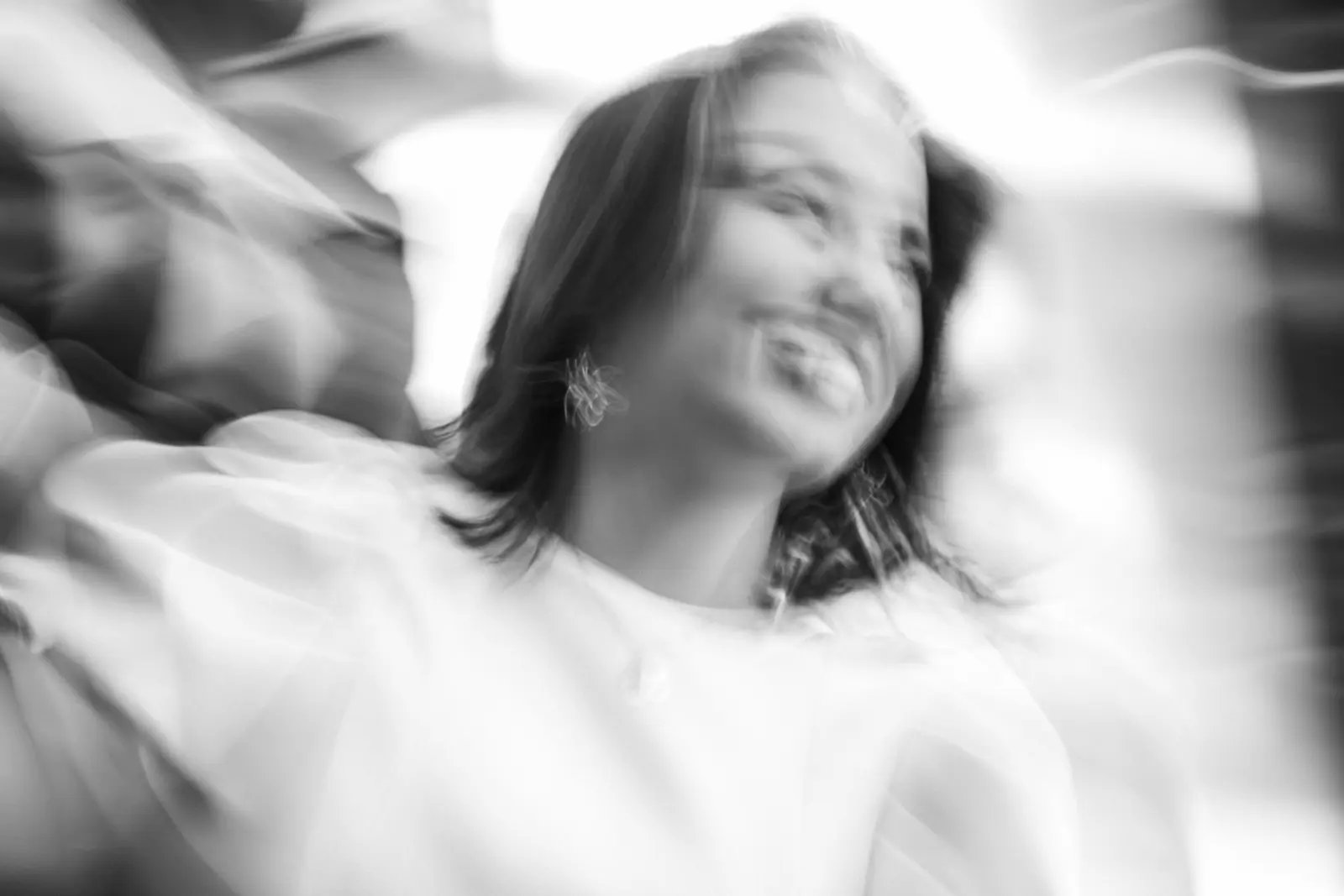 Retrato en movimiento de una novia sonriendo durante su boda, fotografía artística en blanco y negro