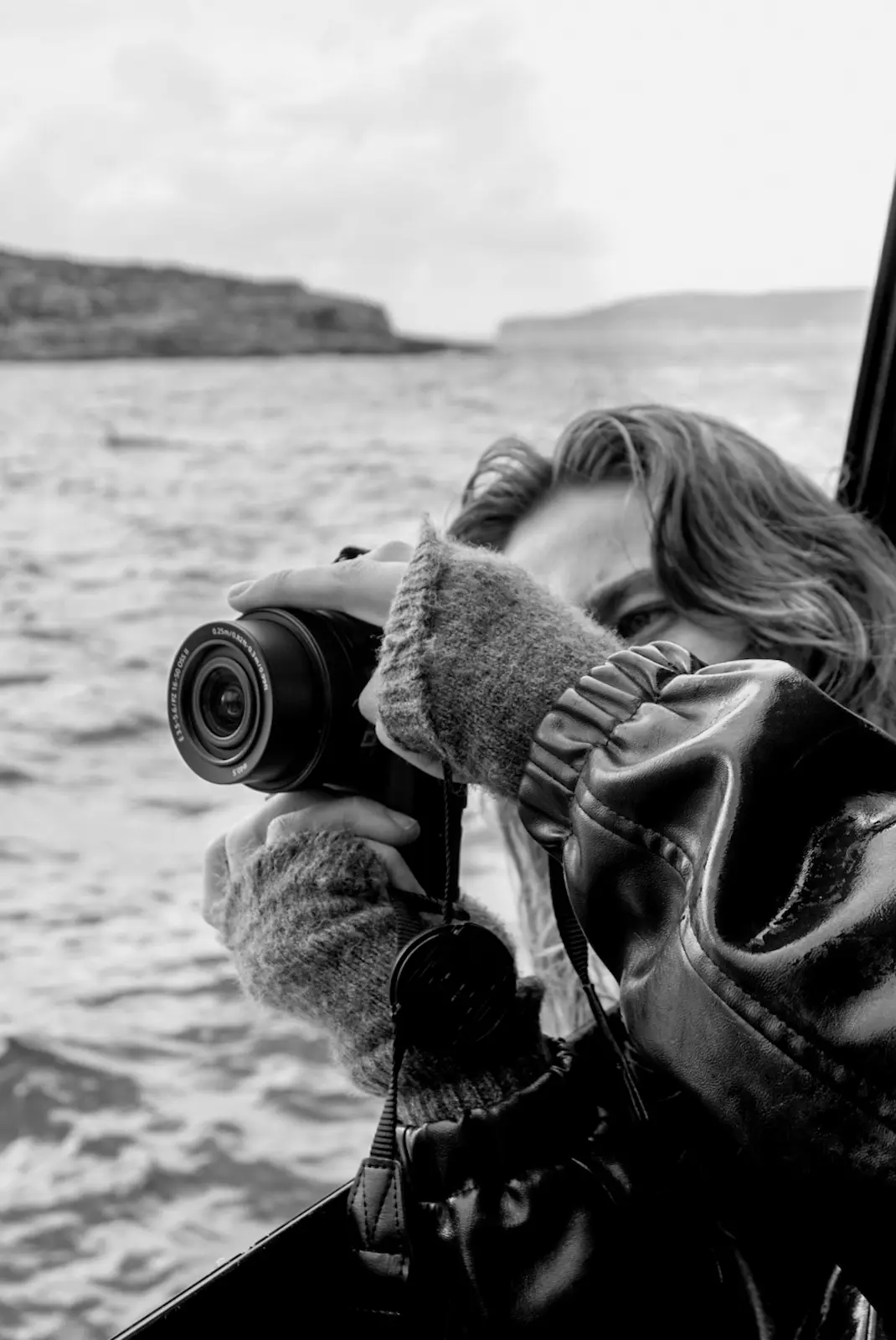 Fotógrafa Camino con cámara en mano fotografiando desde un barco en el mar, retrato en blanco y negro